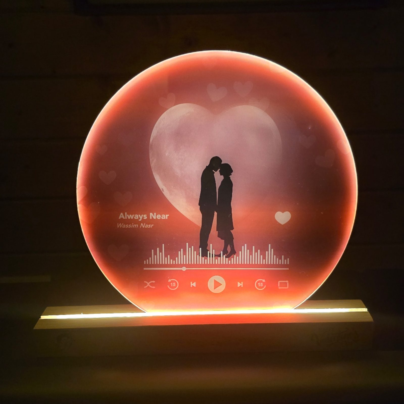 Backlit moon lamp with a couple silhouette and music player interface.